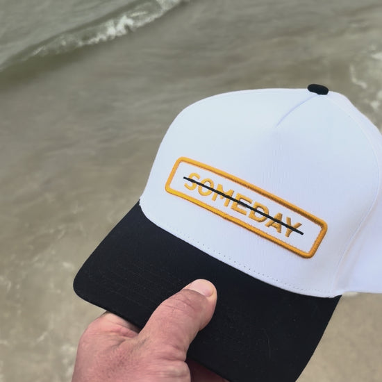 video of the "someday" hat, with the word crossed out being shown with the ocean in the background.