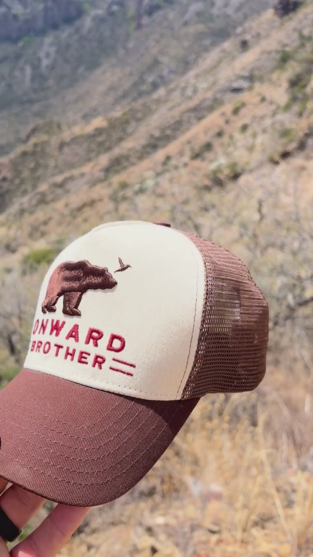 Video of someone holding the Brown Bear Trucker Hat and showing inside and outside of it with Big Bend mountains in the backgroud.