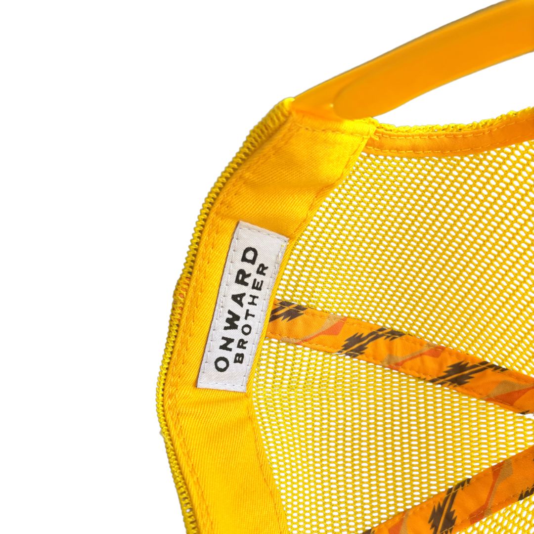 Close-up of a bright yellow mesh hat inside with a white sewn label reading 'ONWARD BROTHER' and orange patterned straps visible against a white background.