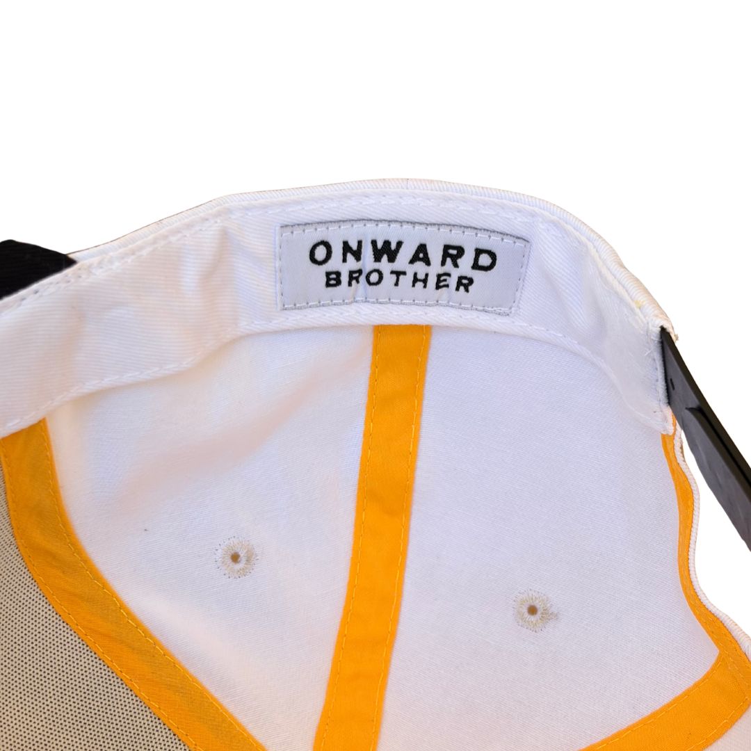 Close-up of the inside of a baseball cap showing a white fabric crown with a yellow-orange center stripe, mesh side panels, and a sewn-in label reading 'ONWARD BROTHER'.